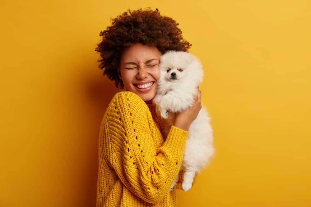 smiling woman holding small white dog